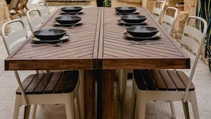 Une table à manger pour quatre personnes, avec des chaises, un mur en pierre et une petite fontaine en arrière-plan.