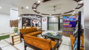 A lobby with seating, a reception desk, and a wall with tourist information. - Hotel Kabeer New Delhi Railway Station  (New Delhi)