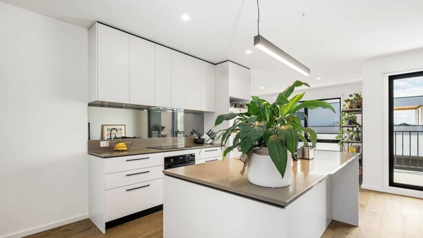 Una cocina moderna con armarios blancos, una isla central y un amplio ventanal con vistas.