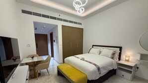 A modern bedroom with a bed, bedside table, and a desk with a chair. - Azizi  405 Fully Furnished Apartment (Dubai)