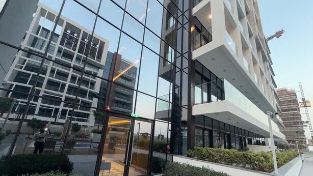 A modern building with large glass windows and a reflective facade. - Azizi  405 Fully Furnished Apartment (Dubai)