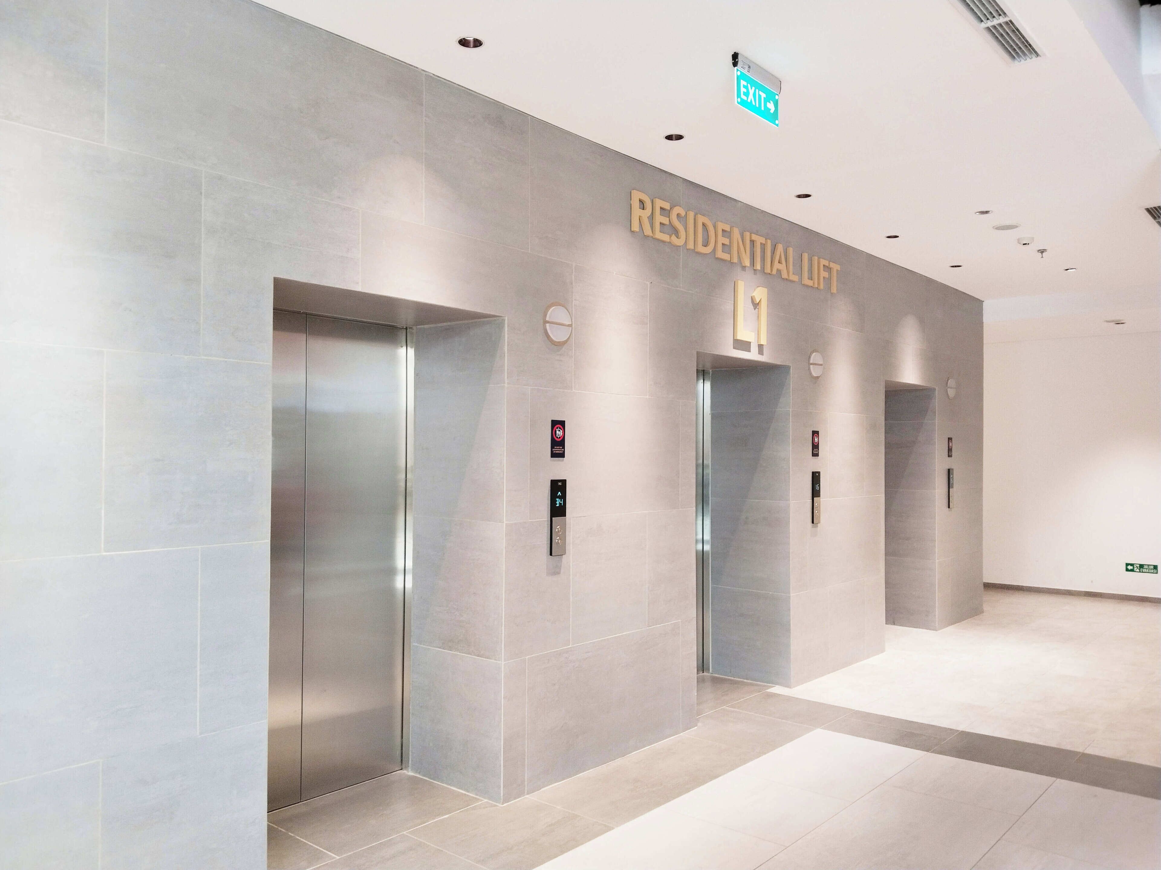 A modern elevator area with a sign reading "RESIDENTIAL LIFT" and an exit sign above.