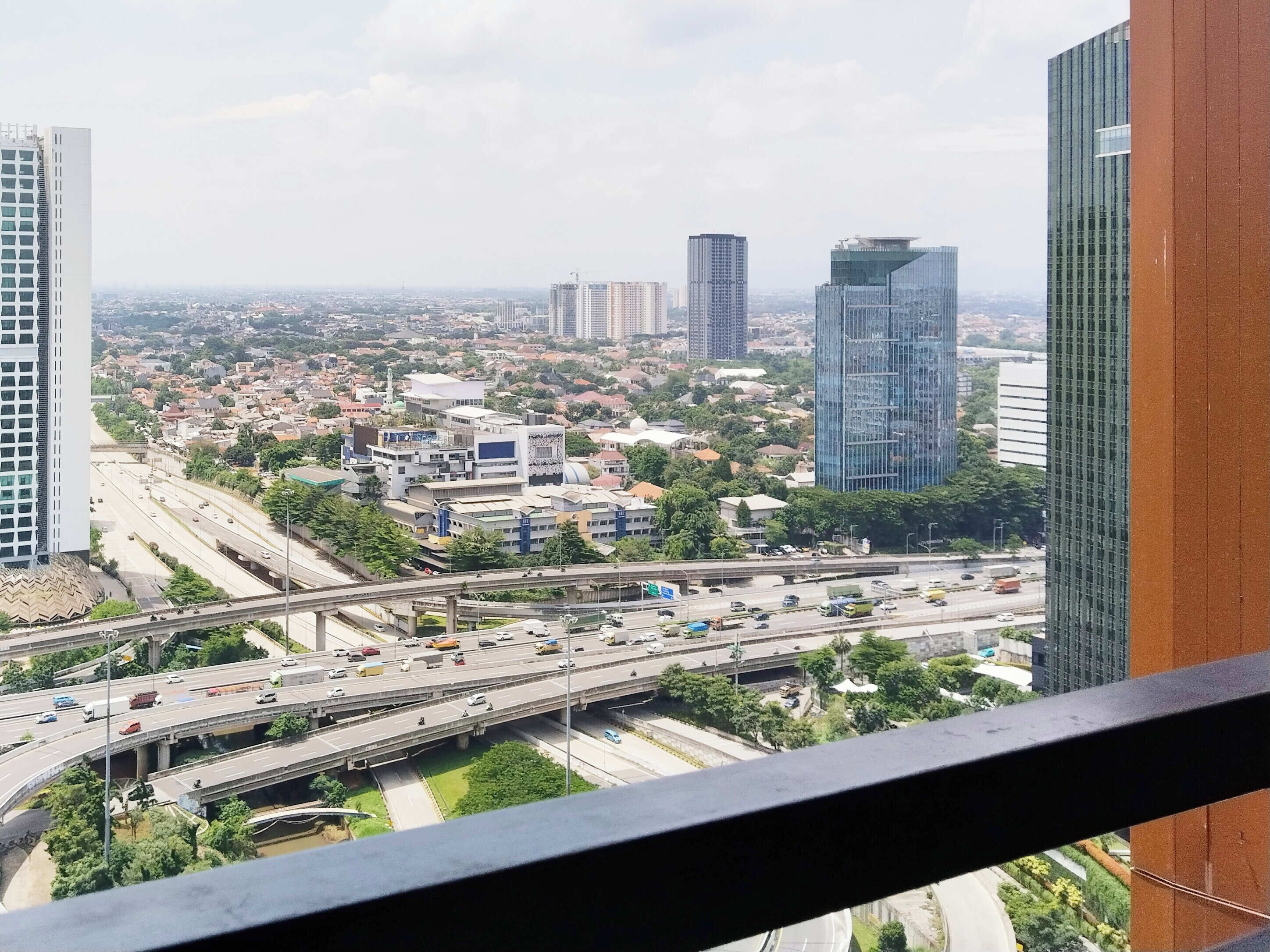 Un paisaje urbano con edificios modernos de gran altura, una autopista con mucho tráfico y una combinación de construcciones residenciales y comerciales.