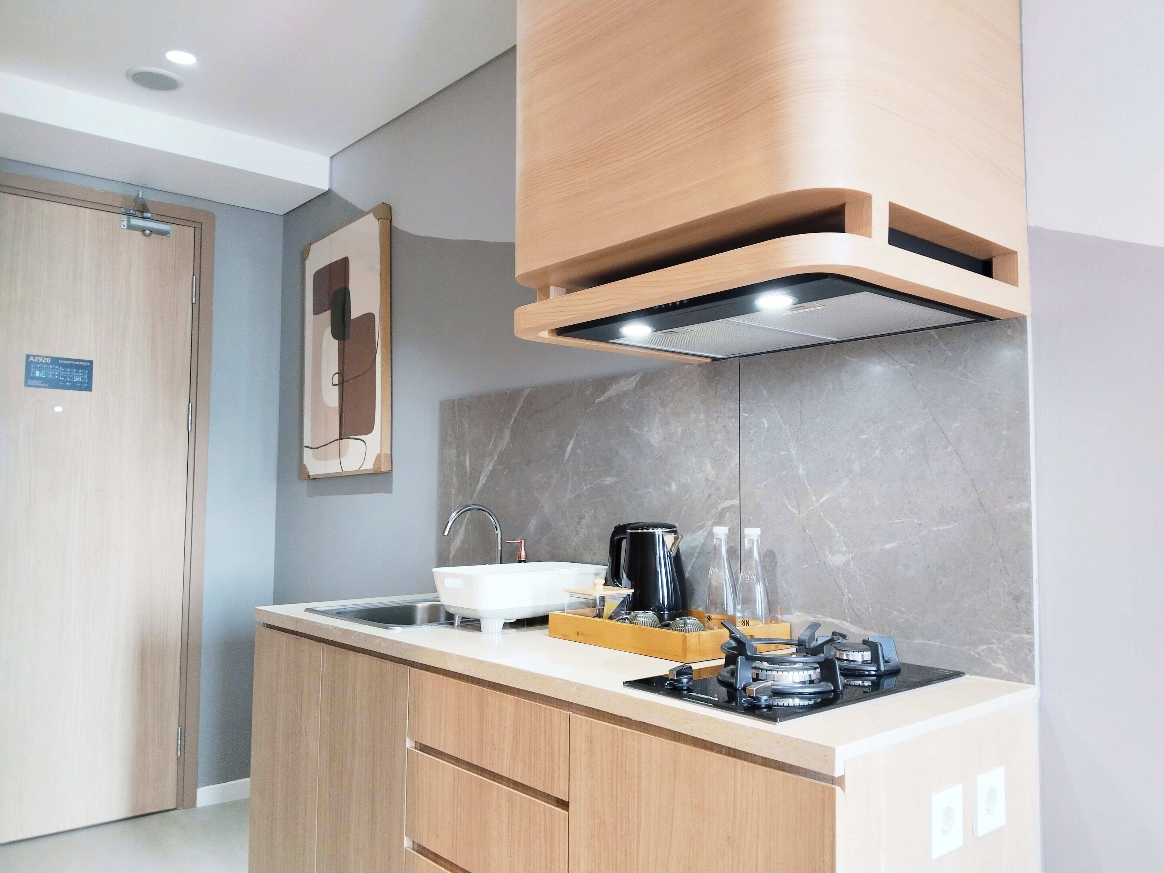 A modern kitchen with wooden cabinets, a stainless steel sink, a gas stove, and a marble backsplash.