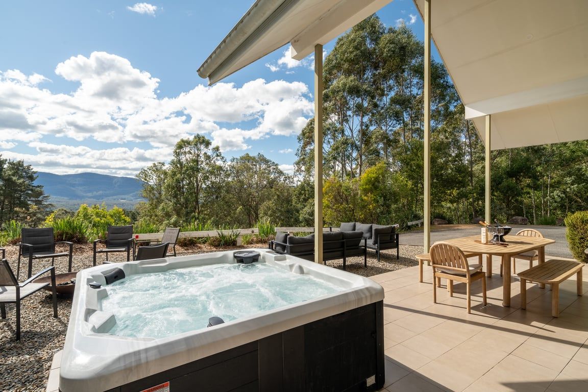 Un bain à remous avec vue sur les montagnes, un espace salon extérieur et une pergola.