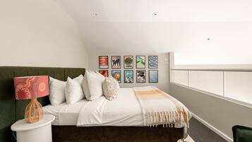 A bedroom with a bed, pillows, a lamp, a rug, and wall art.