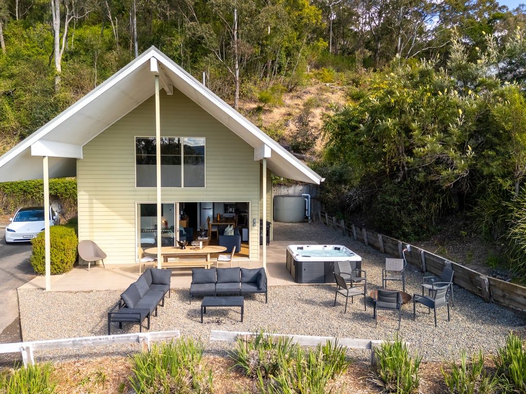A two-story house with a patio area featuring outdoor furniture and a hot tub.