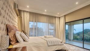 A bedroom with a large bed, a glass partition, and a view of the outdoors. - A spacious, private home tucked just moments from Umhlanga’s coastline. (Durban)