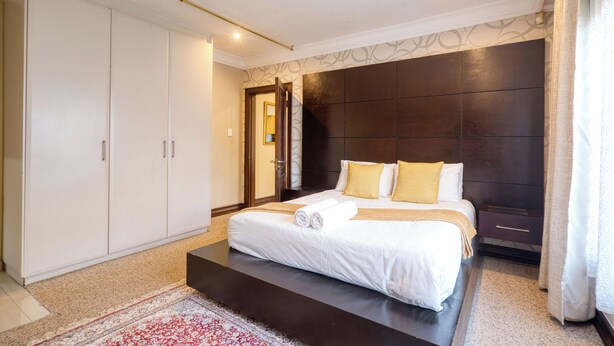 A modern bedroom with a large bed, a wardrobe, and a dark accent wall. - A spacious, private home tucked just moments from Umhlanga’s coastline. (Durban)