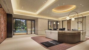 Un moderno vestíbulo de hotel con mostrador de recepción, ventanas amplias y vistas al exterior.