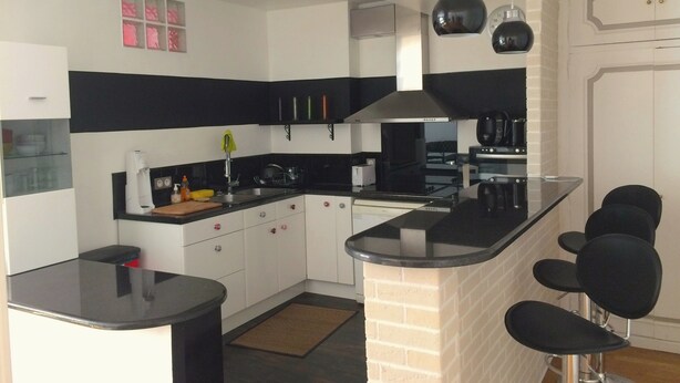 A modern kitchen with a black countertop, white cabinets, and a brick accent wall.