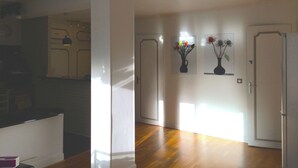 A spacious room with hardwood flooring, a kitchen area, and two doors leading to other rooms.