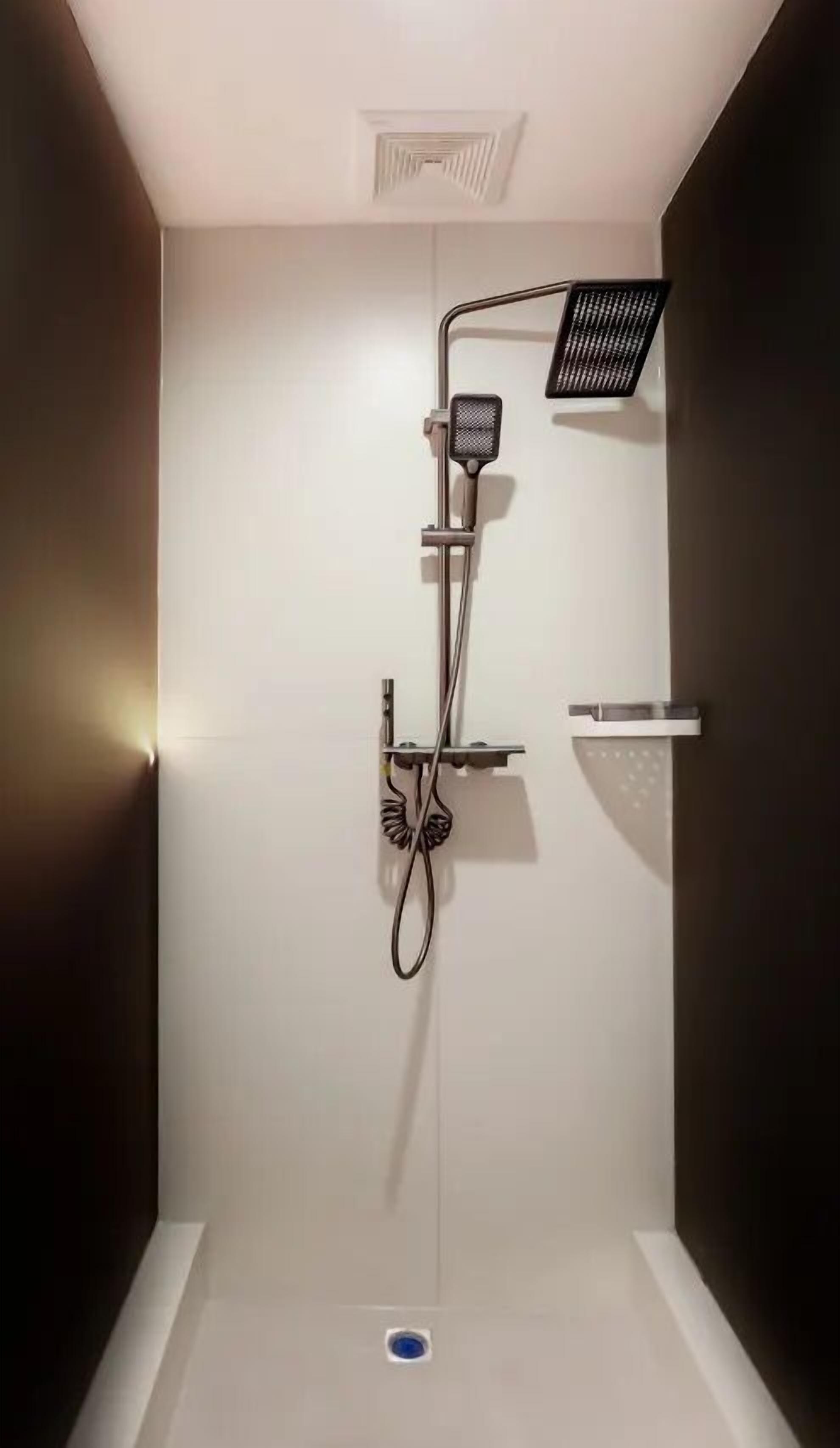 En modern dusch med ett duschhuvud som kan hållas i handen, en väggmonterad kontrollpanel och ett löstagbart duschmunstycke.