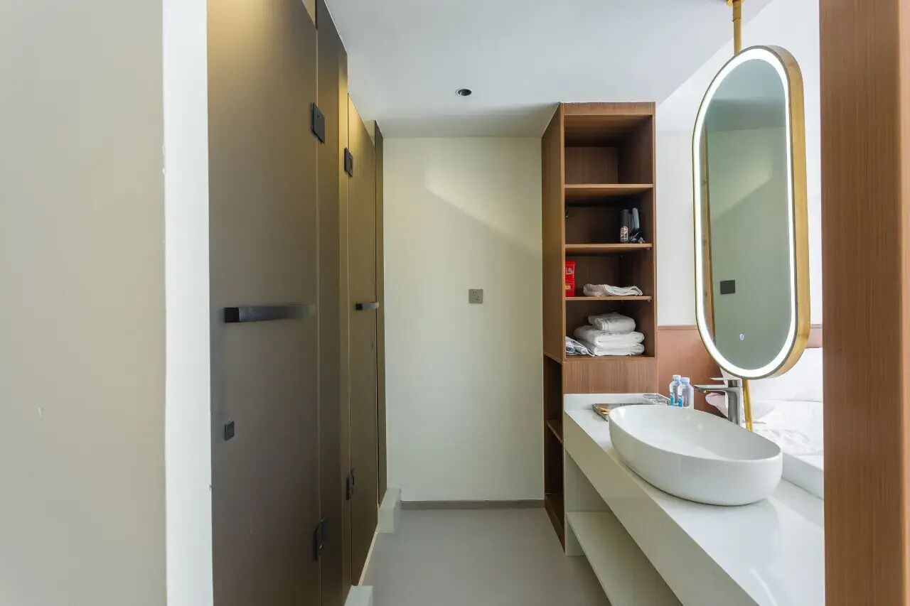 A modern bathroom with a built-in sink, a mirror, and wooden shelving.