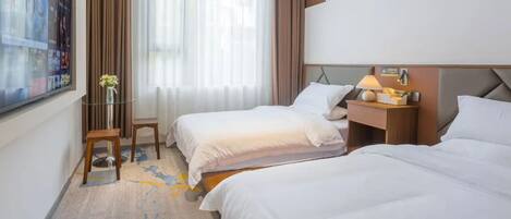 Habitación de hotel con dos camas, televisión, una mesita con un florero y ventana con cortinas.