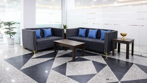 A modern lobby with a dark grey sofa set, a wooden coffee table, and a small side table with a golden bowl. The floor has a black and white geometric pattern. - Axon Stays Near Artemis Hospital Gurgaon Sector 52 (Gurugram)