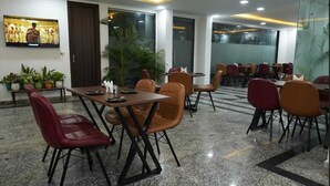 A conference room with a large TV, multiple tables and chairs, and potted plants. - Axon Stays Near Artemis Hospital Gurgaon Sector 52 (Gurugram)