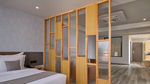 A modern hotel room with a large bed, a wooden partition, and a bathroom visible through a glass door. - Pride Elite Gandhinagar (Gandhinagar)