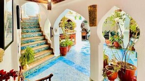 A spacious interior with a patterned floor, a staircase, and multiple arches. - Riad Dar Meziana  (Chefchaouen)