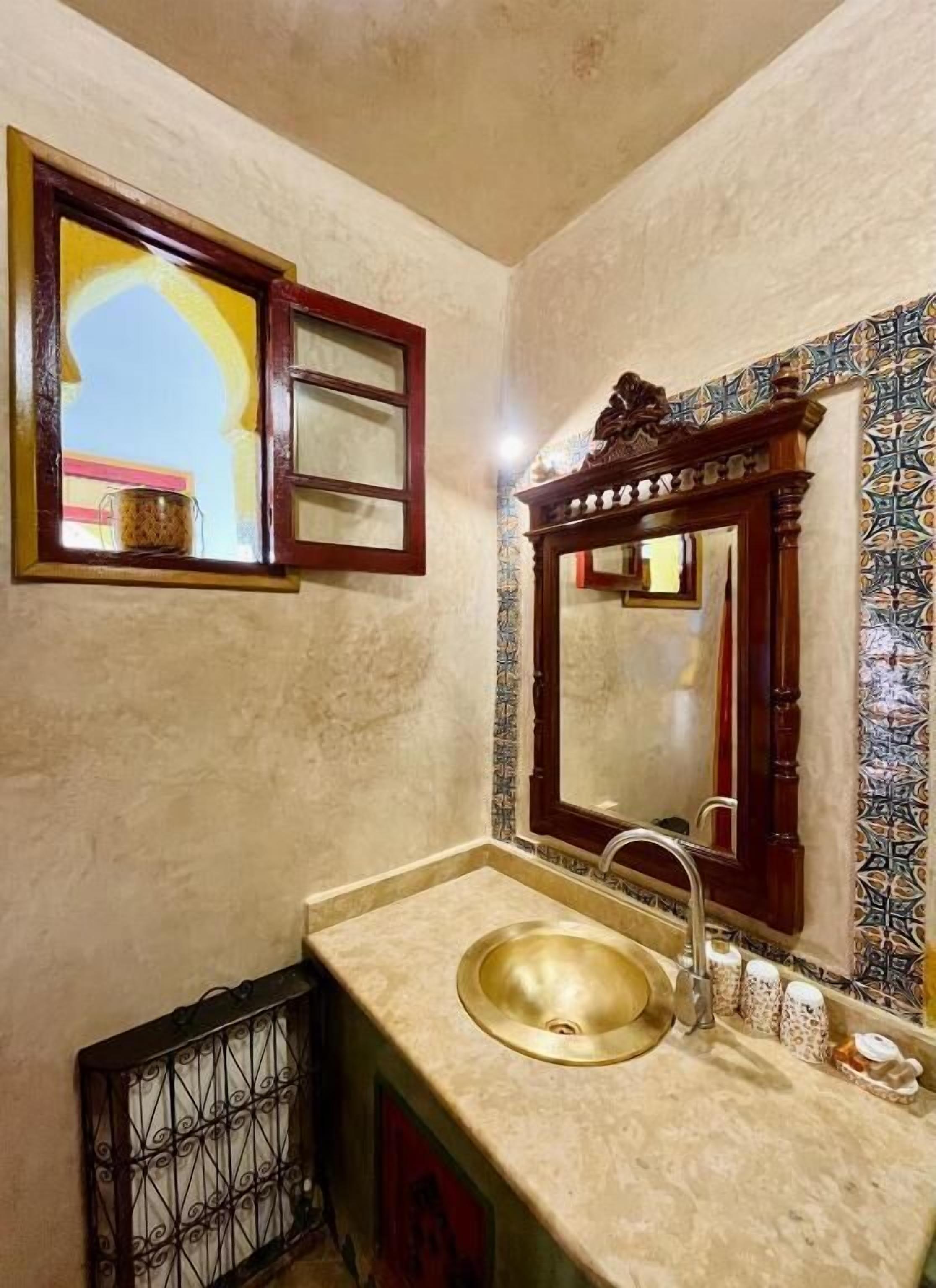 Une salle de bain avec un lavabo, un miroir et une fenêtre donnant sur un beau paysage.