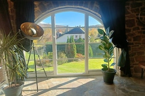 A room with a large arched window, a potted plant, and a floor lamp.