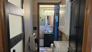 A narrow hallway with a washing machine, a dryer, and a small kitchen area with a sink and cabinets. - Phenomenal 2-bedroom cabin in Saint Helen, the heart of northern Michigan. (St. Helen)