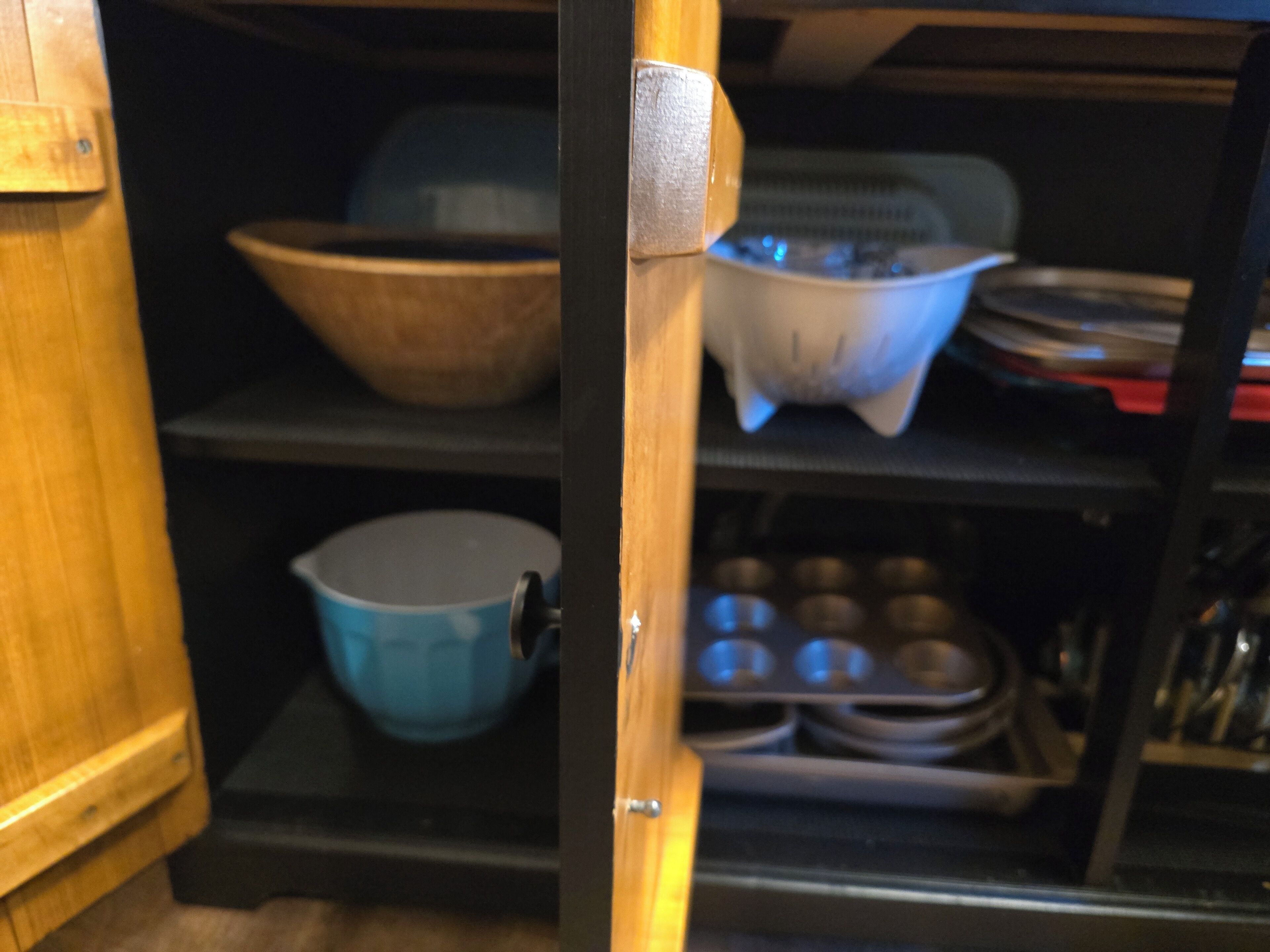Eine Küche mit Holzausstattung, einer blauen Schüssel, einem weißen Topf und einer Muffin-Form.