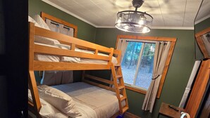 A bunk bed room with a wooden ladder, a desk with a chair, a patterned rug, and a window with curtains. - Phenomenal 2-bedroom cabin in Saint Helen, the heart of northern Michigan. (St. Helen)