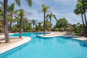 Ein Swimmingpool mit Palmen, Liegestühlen und blauem Himmel.