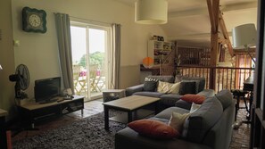 A living room with a sofa, coffee table, and a television. There is a bookshelf and a staircase in the background. - LARGE BEARNAISE COUNTRY HOUSE (SAUVELADE)