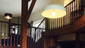 A spacious living room with a high wooden ceiling, a fireplace, a staircase, and a cozy seating area with a sofa and cushions. - LARGE BEARNAISE COUNTRY HOUSE (SAUVELADE)