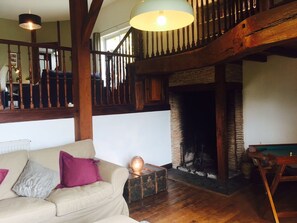 A cozy living room with a wooden staircase, a fireplace, and a sofa with cushions. - LARGE BEARNAISE COUNTRY HOUSE (SAUVELADE)