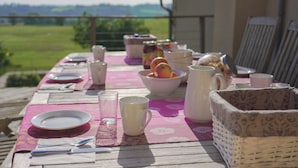 A wooden table set for a meal with plates, cutlery, glasses, and a bowl of fruit. - LARGE BEARNAISE COUNTRY HOUSE (SAUVELADE)