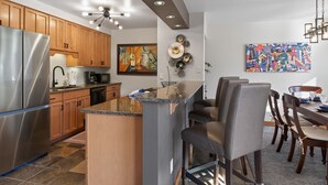 Een moderne keuken met houten kastjes, een roestvrijstalen koelkast en een centraal kookeiland met barstoelen.