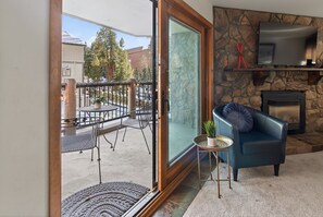 A living room with a stone fireplace, a blue sofa, and a television mounted on the wall. - In the middle of it all. Walk. Ski in. Hot Tubs. (Breckenridge)