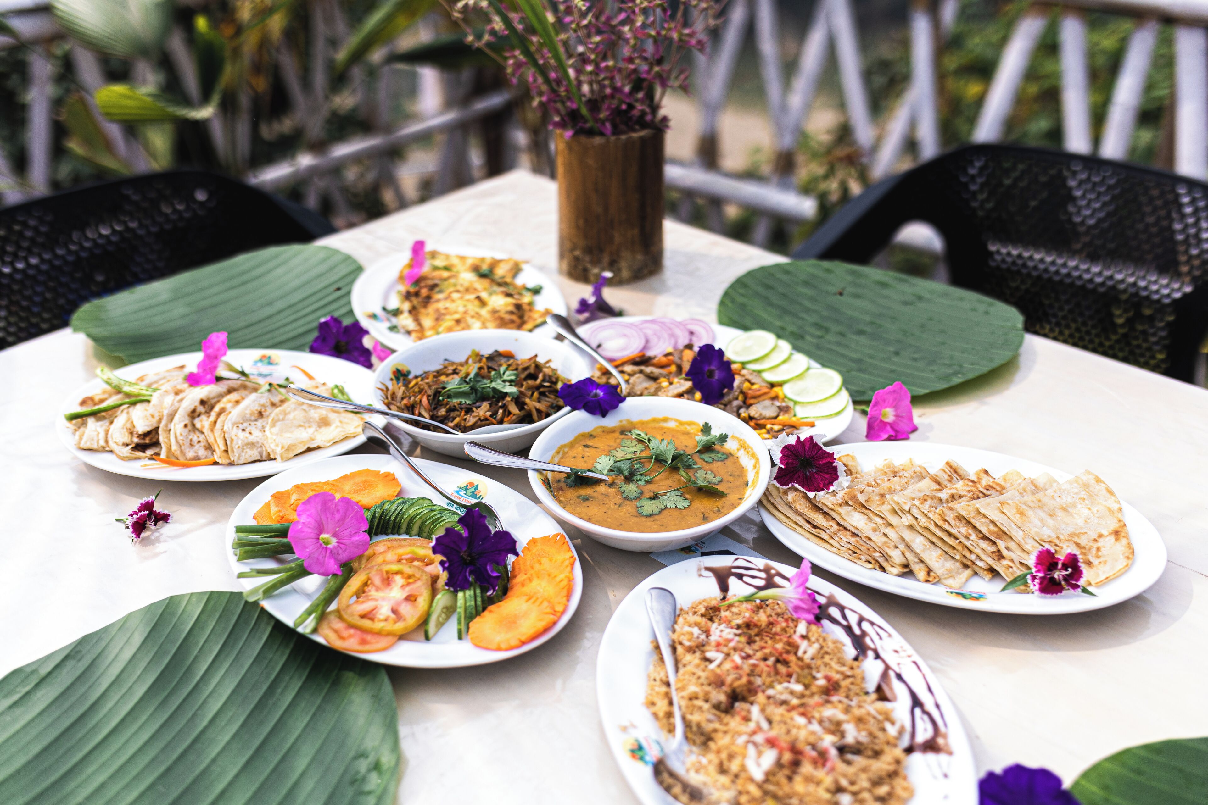A table set with various dishes, including a bowl of soup, a plate of flatbreads, and a dish with sliced vegetables and meat.