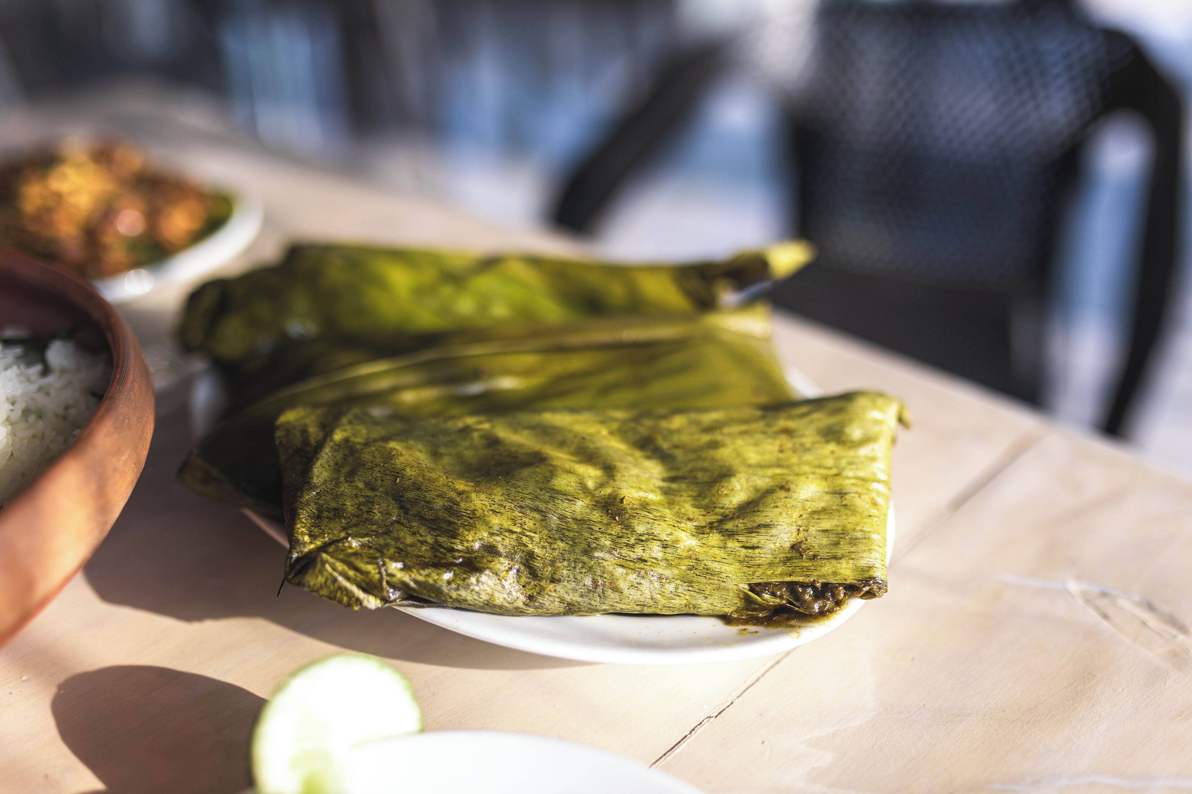 Tamales wrapped in corn husks on a white plate.