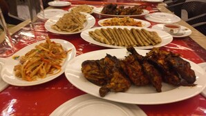 Un tavolo con diversi piatti, tra cui pollo alla griglia, piadine e un'insalata.