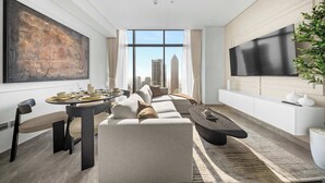 Una sala de estar moderna con un cuadro grande, un conjunto de sofás, una mesa de comedor y un televisor montado en la pared.