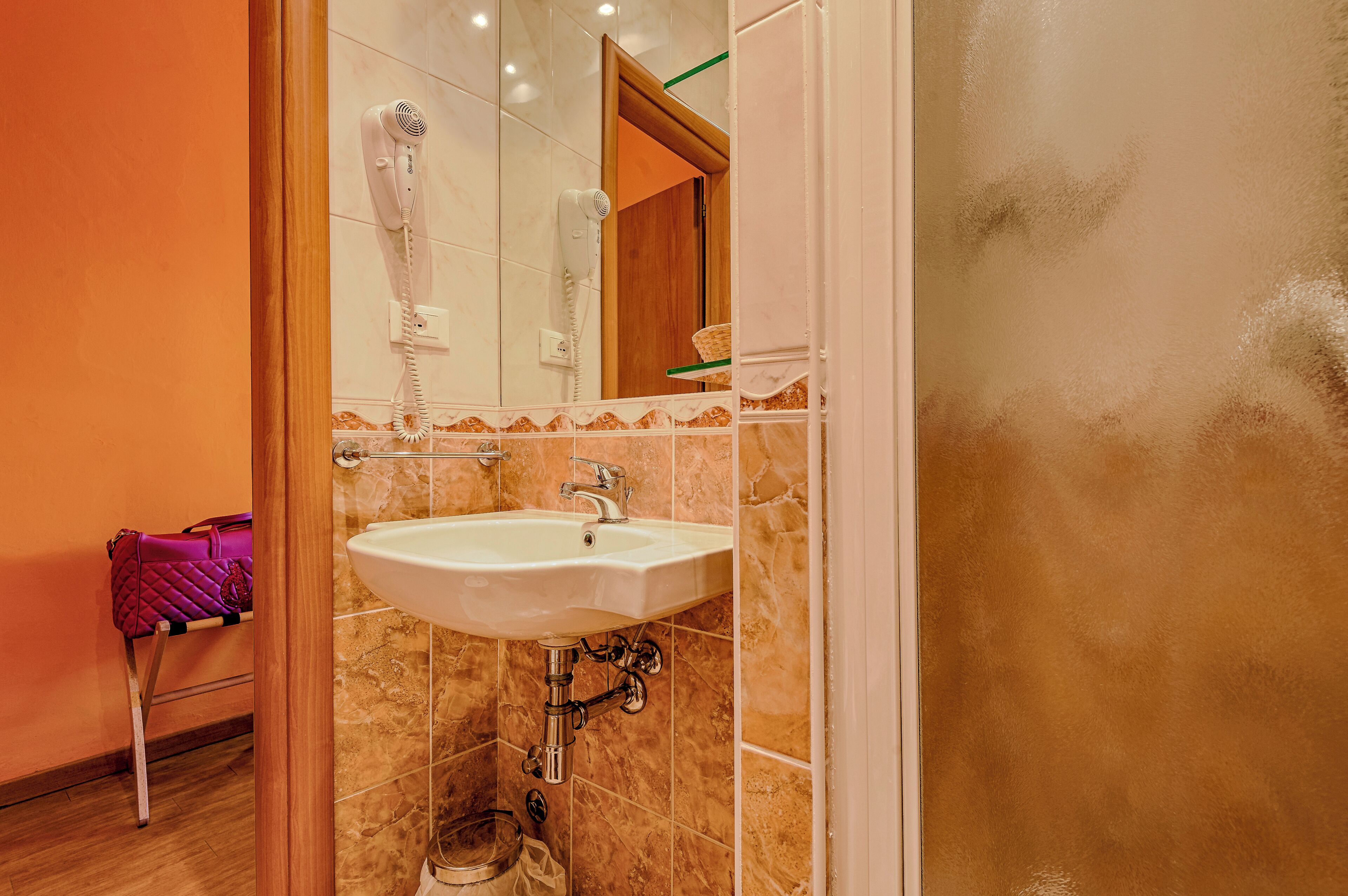 Une salle de bain avec un lavabo blanc, un sèche-cheveux et un porte-serviettes.