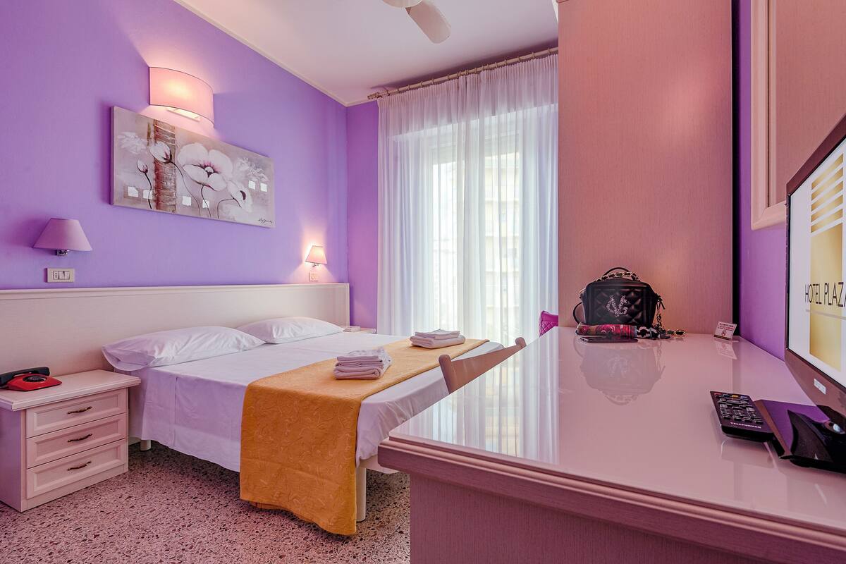 Une chambre d’hôtel avec un lit, une table de chevet, une lampe et un tableau au mur.