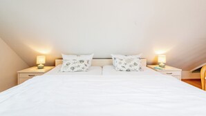 Quarto com cama, duas mesas de cabeceira, luminárias e almofadas combinando.