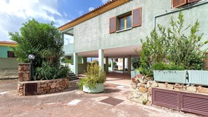 A building with a stone facade, multiple windows with shutters, and a covered outdoor area with potted plants. - Apartment 'Della Torre 40T' (isola rossa)