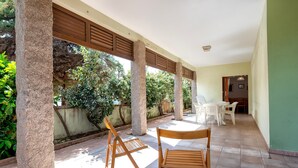 A covered outdoor area with stone pillars, wooden benches, and a table with chairs. - Apartment 'Della Torre 40T' (isola rossa)