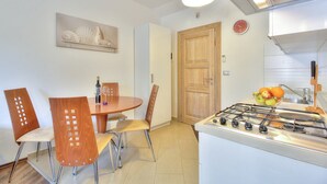 A compact kitchen with a gas stove, a dining table with chairs, and a wooden door. - Cosy studio apartment for 2 on a great location in a touristic village, Susanna1 (Katoro)
