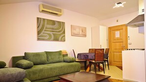 A living room with a green sofa, a wooden coffee table, and a dining area with a table and chairs. - Cosy studio apartment for 2 on a great location in a touristic village, Susanna1 (Katoro)