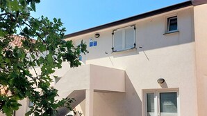 A building with a white exterior, a small window with shutters, and a door with a metal handle. - Cosy studio apartment for 2 on a great location in a touristic village, Susanna1 (Katoro)