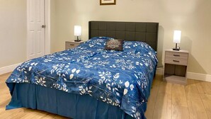 Quarto com uma cama, duas mesas de cabeceira e uma porta.