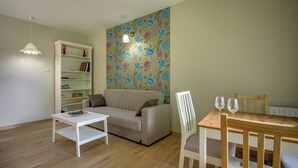 Un salon comprenant un canapé, une table basse, une bibliothèque et une table à manger avec des chaises.