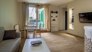 Un salon comprenant un canapé, une table basse, un téléviseur et un balcon offrant une vue sur les immebles.
